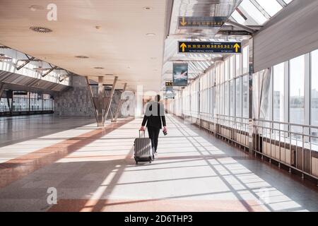 Uomo che trasporta i suoi bagagli attraverso il terminal dell'aeroporto Foto Stock