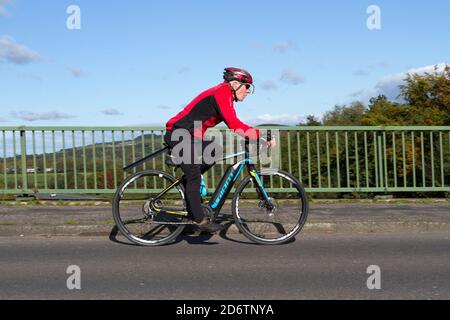 Cavalcare il ciclista maschile Giant in fibra di carbonio leggero sport bici da strada sulla strada di campagna che attraversa il ponte autostradale nel Lancashire rurale, Regno Unito Foto Stock