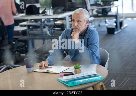 Uomo d'affari senior premuroso che prende appunti in ufficio Foto Stock