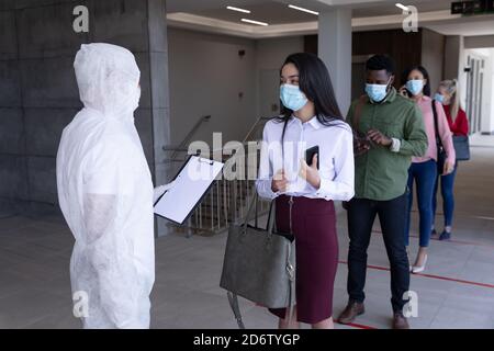 Gruppo di persone che indossano maschere in coda Foto Stock