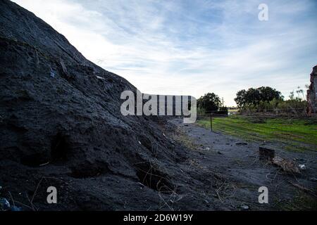 Montagne di carbone scarico con prato verde a destra Foto Stock