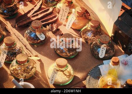 Una varietà di spezie sono in vasi con etichette. Bottiglie firmate di condimenti sul mercato. Vendita di spezie in un giorno di sole. Foto Stock