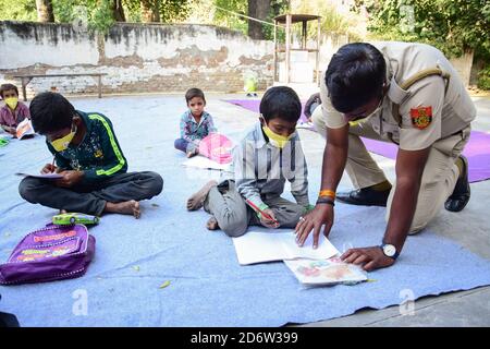 La polizia di Delhi costable 'che Singh' visto indossare un facemask mentre insegnano i bambini in una classe aperta durante la pandemia di Covid19.A la polizia di Delhi costable 'che Singh' ha organizzato classi di scuola aperta per i bambini incapaci di permettersi l'istruzione in linea durante la pandemia di Covid19. La maggior parte degli studenti che frequentano queste classi sono figli di lavoratori, che vivono nella zona dietro la Redford Nuova Delhi, che non può permettersi smartphone e computer, questo ha costretto il conestabile a riprendere le lezioni a scuola aperta. Le lezioni sono eseguite dal 'tempio sai' nell'area parcheggio del Forte Rosso di Delhi. Foto Stock