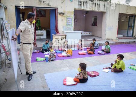 La polizia di Delhi costable 'che Singh' visto indossare un facemask mentre insegnano i bambini in una classe aperta durante la pandemia di Covid19.A la polizia di Delhi costable 'che Singh' ha organizzato classi di scuola aperta per i bambini incapaci di permettersi l'istruzione in linea durante la pandemia di Covid19. La maggior parte degli studenti che frequentano queste classi sono figli di lavoratori, che vivono nella zona dietro la Redford Nuova Delhi, che non può permettersi smartphone e computer, questo ha costretto il conestabile a riprendere le lezioni a scuola aperta. Le lezioni sono eseguite dal 'tempio sai' nell'area parcheggio del Forte Rosso di Delhi. Foto Stock