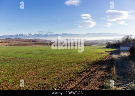 Paesaggio con vista sul monte Rila in Bulgaria,. Verde terreno e montagne innevate all'orizzonte. Vista dal villaggio di Logodazh Foto Stock