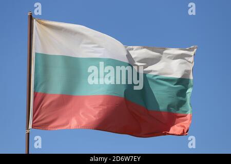 Bandiera bulgara che vola su flagpole su sfondo blu cielo Foto Stock