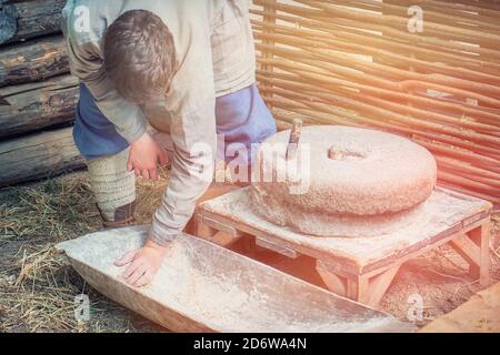 Uomo per macinare la farina sui mulini a mano. Vita rustica per la produzione di pane macinando i grani in farina. Foto Stock