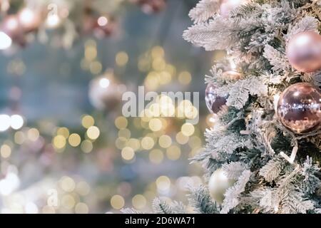 Albero di natale decorato e illuminato su morbido sfondo dorato sfocato. Baubles e luci sul ramo dell'albero. Buon anno o buon natale Foto Stock