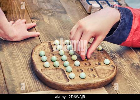 Due persone giocano un antico gioco da tavolo Mill. Ricostruzione di intrattenimento e tempo libero nei vecchi tempi. Gioco intellettuale vintage per due giocatori. Foto Stock