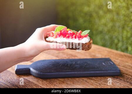 La donna tiene la bruschetta, colazione italiana in un caffè estivo Foto Stock