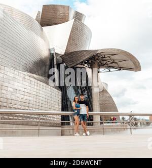 Coppia che visita l'esterno del museo Guggenheim a Bilbao, Spagna Foto Stock