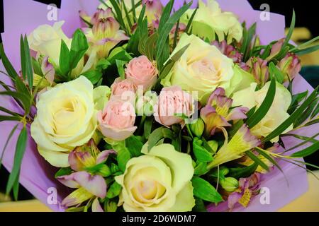 Bouquet di rose e gigli da vicino. Bellissimi fiori con foglie verdi. Rose gialle e rosa, gigli di Borgogna. Foto Stock