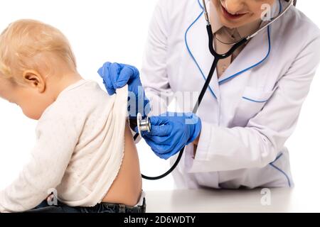 Un pediatra sorridente che esamina la schiena del bambino con stetoscopio isolato su bianco Foto Stock