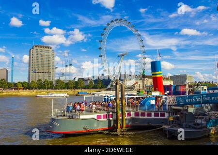 Tamigi e South Bank con London Eye bella estate Giorno visto da Victoria Embankment vicino a un ex traghetto passeggeri ormeggiato con cibo da pub e bevande Foto Stock