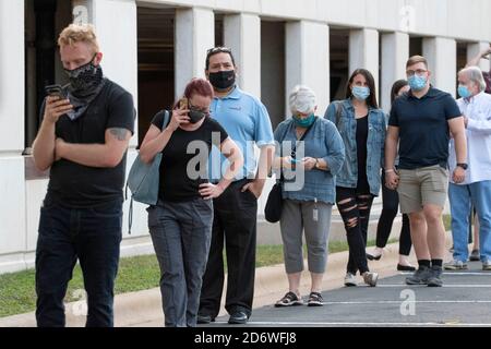 Austin, Texas USA, ottobre 13 2020: I texani mascherati attendono pazientemente in fila nella zona di Arboretum nel nord di Austin in un sito di voto precoce per lanciare i voti nelle elezioni presidenziali del 2020. I funzionari riportano un numero record di elettori in anticipo con quasi 40,000 al giorno in tutta la città. Foto Stock