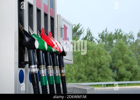 Concetto di benzina e prodotti petroliferi. Pistole di carburante rosse e nere sulla stazione di rifornimento. Per riempire l'auto con benzina. Primo piano. Foto Stock