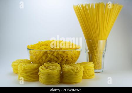 Pasta gialla su fondo bianco. Diversi tipi di pasta. Foto Stock