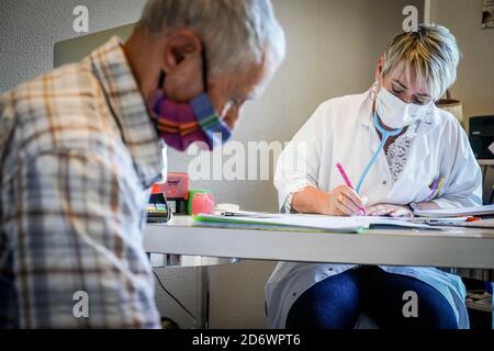 Uomo in consultazione con un medico generico che indossa una maschera chirurgica, Francia, maggio 2020. Foto Stock