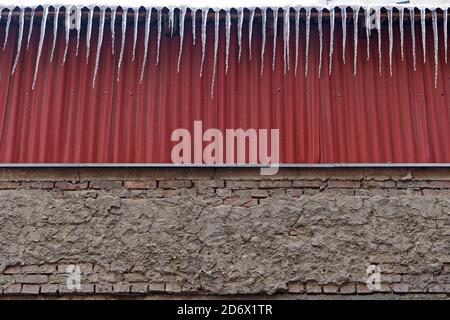 I pericolosi icicles appendono ai pericoli del tetto dell'edificio Foto Stock