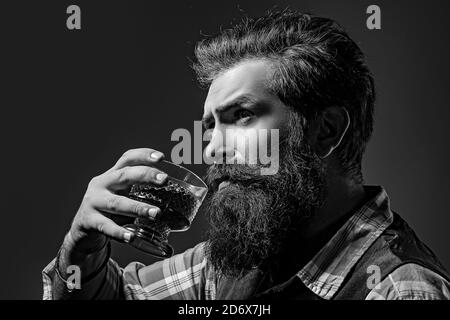 Il barista uomo con la barba trattiene il brandy di vetro. Il sommelier ha un gusto alcolico costoso. Foto Stock