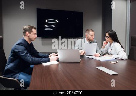 La gente di affari che lavorano insieme sul loro computer portatile in una sala riunioni Foto Stock