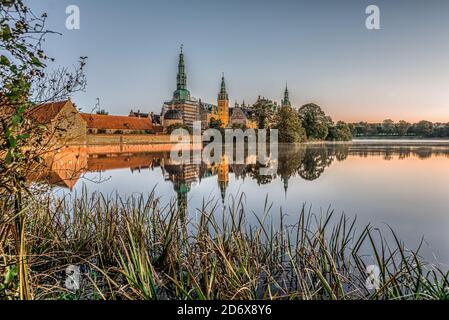 Il lago velato di Frederiksborg con canne e il castello sullo sfondo una tranquilla mattina di ottobre all'alba, Hillerod, Danimarca, 17,2020 ottobre Foto Stock