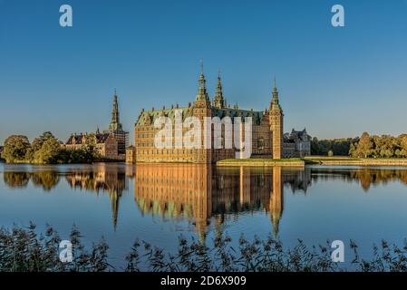 Il castello di Frederiksborg riflette nel lago una mattina senza vento al sole e un gabbiano nuoterà in acqua, Hillerød, Danimarca, 17 ottobre 2020 Foto Stock