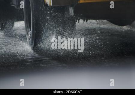 Ruote di un camion che guida su una strada bagnata in condizioni di pioggia. Schizzi che volano da sotto gli pneumatici. Foto Stock