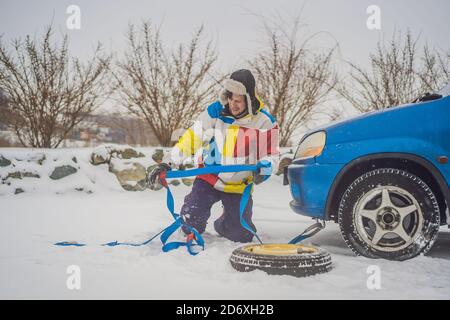 Uomo con ganci per fune di traino vicino all'auto trainata Foto Stock