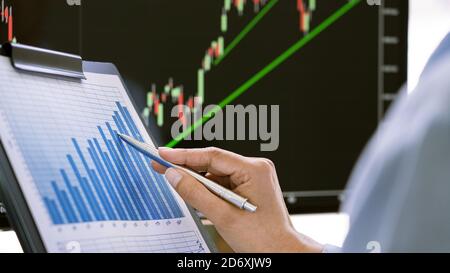 Stock Market Broker in abbigliamento da formalwear analisi grafici su schermi in ufficio, concetto di investimento Foto Stock