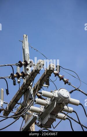 Primo piano linea di elettricità e l'elettricità post all cielo blu sullo sfondo Foto Stock