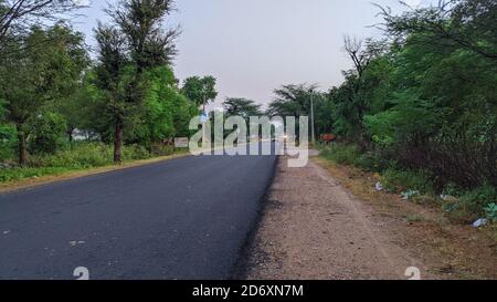 18 Ottobre 2020 : Reengus, Jaipur, India / bella vista creata dalla strada vuota al mattino. Strada vuota che conduce al villaggio e le nuvole bianche Foto Stock