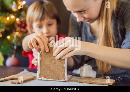 Giovane madre e capretto che fanno la casa del pan di zenzero alla vigilia di Natale Foto Stock