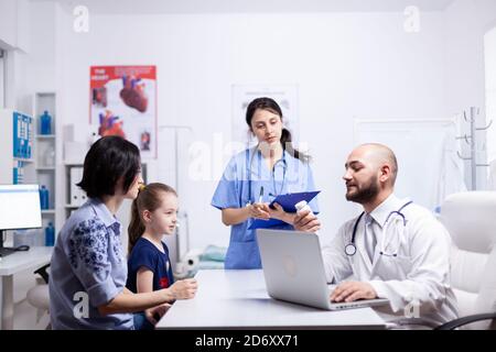 Medico che tiene pillole bottiglia durante la consultazione del bambino in ufficio domestico. . Medico specialista in medicina che fornisce servizi di assistenza sanitaria esame di trattamento. Foto Stock