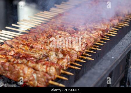 Un sacco di kebab in fila sulla griglia. Kebabs strung su spiedini di legno Foto Stock