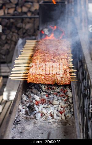 Un sacco di kebab in fila sulla griglia. Kebabs strung su spiedini di legno Foto Stock
