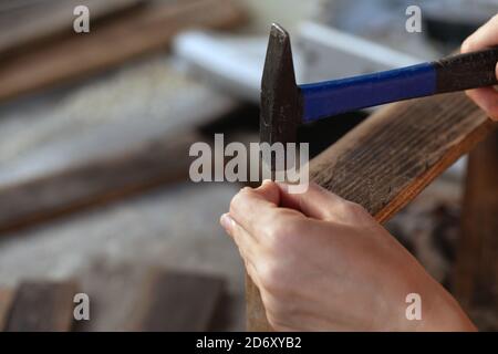 Primo piano di martello chiodo in legno tavola Foto Stock