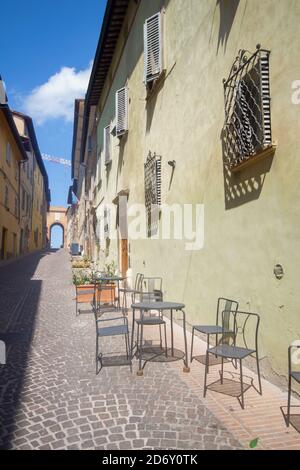 strada tipica di urbino con un'antica porta di rhe città medievale sullo sfondo Foto Stock