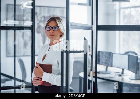 Ritratto di donna d'affari in abiti formali che si trova in ufficio Foto Stock