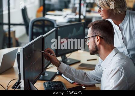 Consente di visualizzare la penna. Due agenti di borsa in abiti formali lavora in ufficio con il mercato finanziario Foto Stock