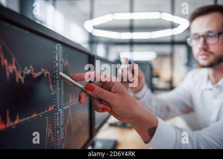 Consente di visualizzare la penna. Due agenti di borsa in abiti formali lavora in ufficio con il mercato finanziario Foto Stock