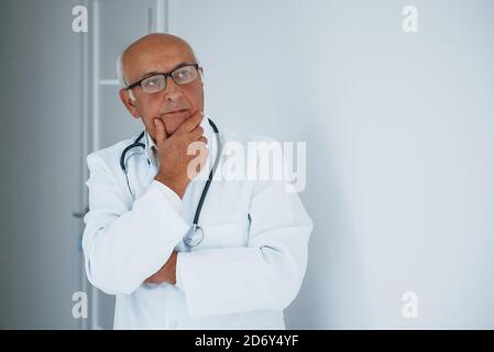 Ritratto di medico senior in uniforme bianca che si trova in piedi la clinica Foto Stock