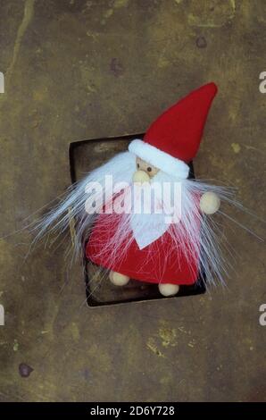 Modello in legno del Padre Natale in rosso e bianco con lunghi baffi bianchi e vistosi giacenti su ottone intaricato Foto Stock