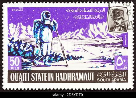 QU'AITI STATE IN HADHRAMAUT - CIRCA 1967: Un francobollo stampato in Yemen mostra astronauta che misura sulla luna, circa 1967. Foto Stock