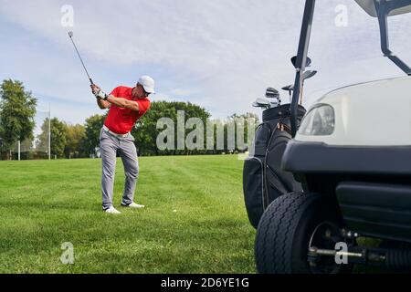 Golfer serio in un cappuccio che colpisce la sfera Foto Stock