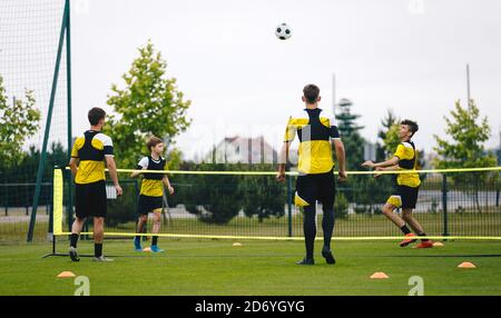 Giovani teenager calciatori che giocano a calcio tennis su un'unità di allenamento. Adolescenti che praticano il calcio sul campo da erba. Ragazzi giovani che giocano sport Foto Stock