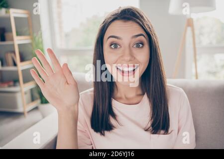 Ritratto fotografico della giovane donna che sventolava dicendo "Ciao seduto" divano interno Foto Stock