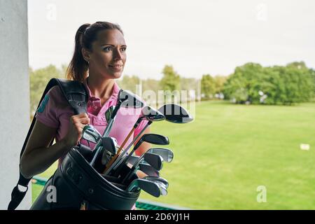 Atleta femminile contented che tiene una borsa di golf Foto Stock