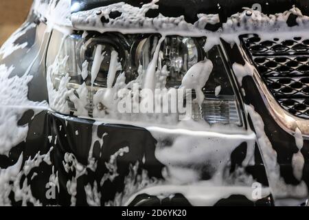Autolavaggio. Schiuma di shampoo sul paraurti dell'auto. Foto Stock