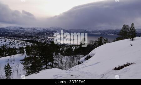 Bella vista panoramica sulla città di alta, Troms og Finnmark, Norvegia dalla collina Komsatoppen con neve-coperto paesaggio e montagne in inverno. Foto Stock